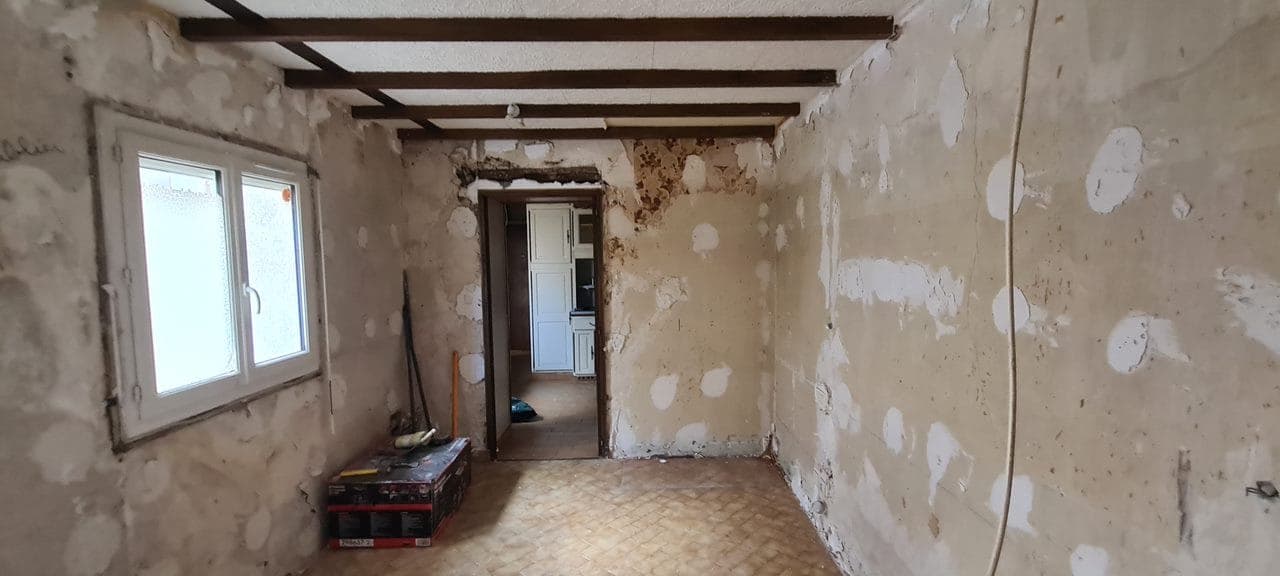 Pièce en cours de travaux, murs mis à nu et poutres apparentes